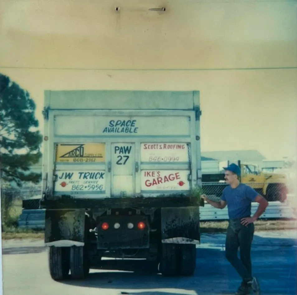 Vintage photo of an early PAW dump truck with the tailgate painted with local business ads and 'PAW 27'